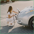 Coface Focus: Will the electric vehicle metals boom last? The photo shows a woman connecting an electric car to an energy source.